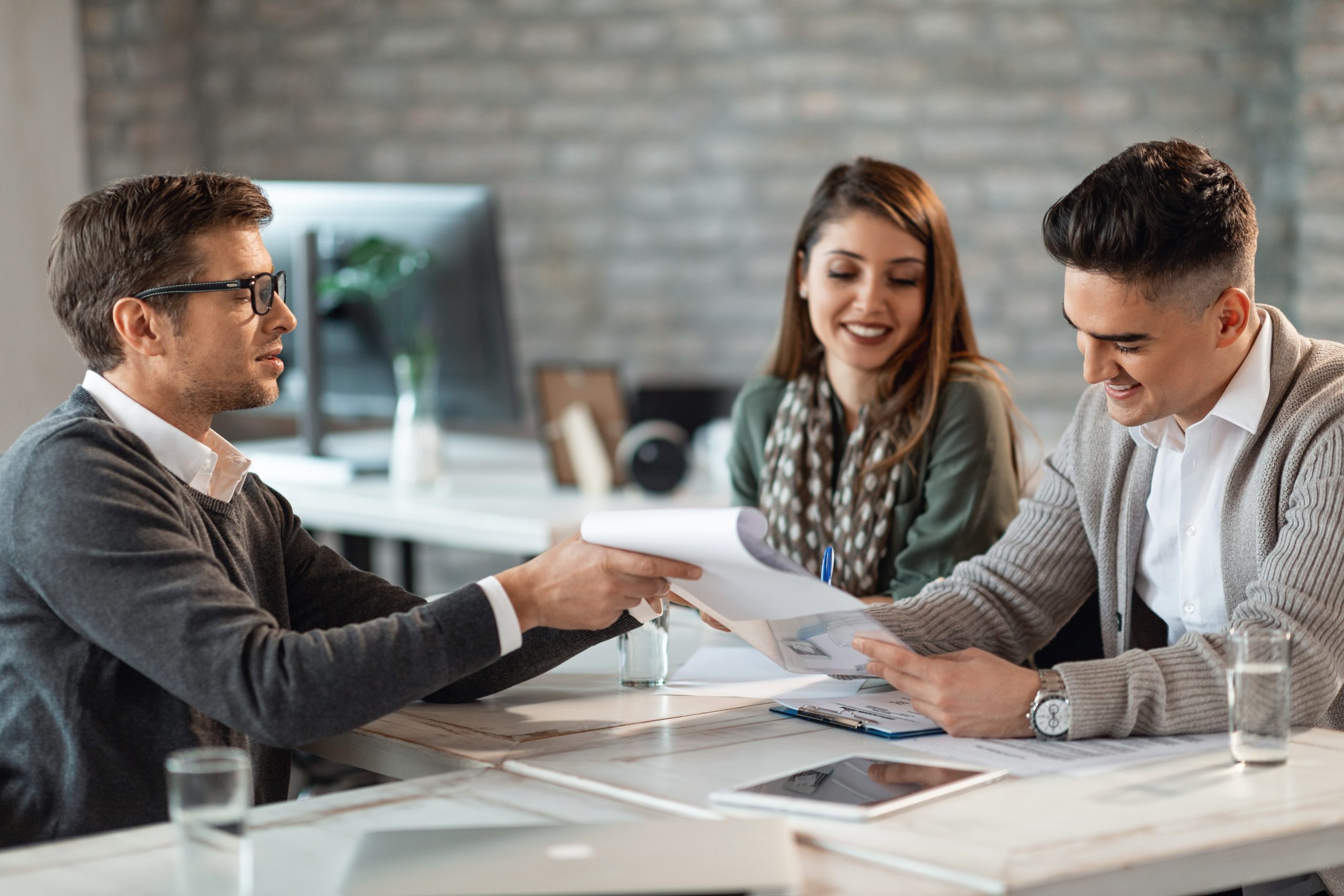 Happy couple signing a contract on a meeting with their real estate agent in the office.